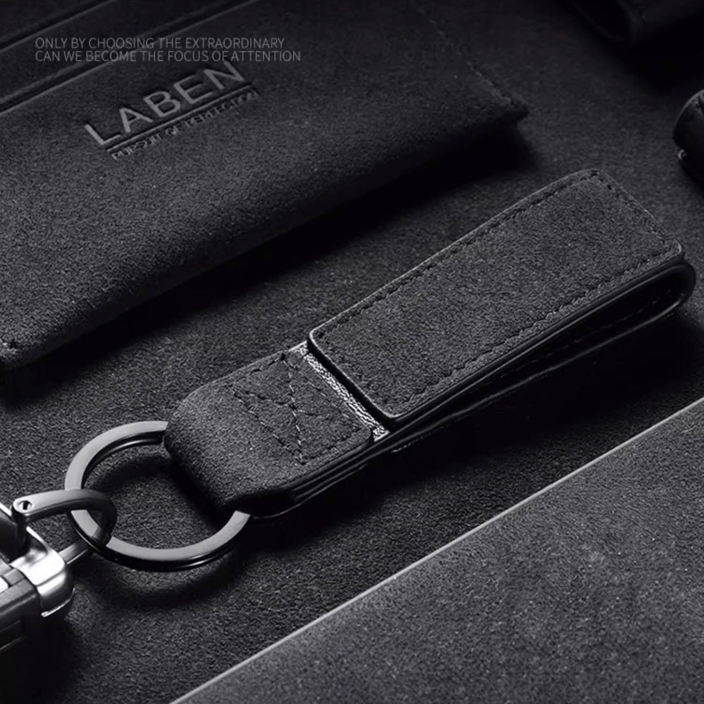 Luxury Alcantara leather car logo keychain on a wooden surface