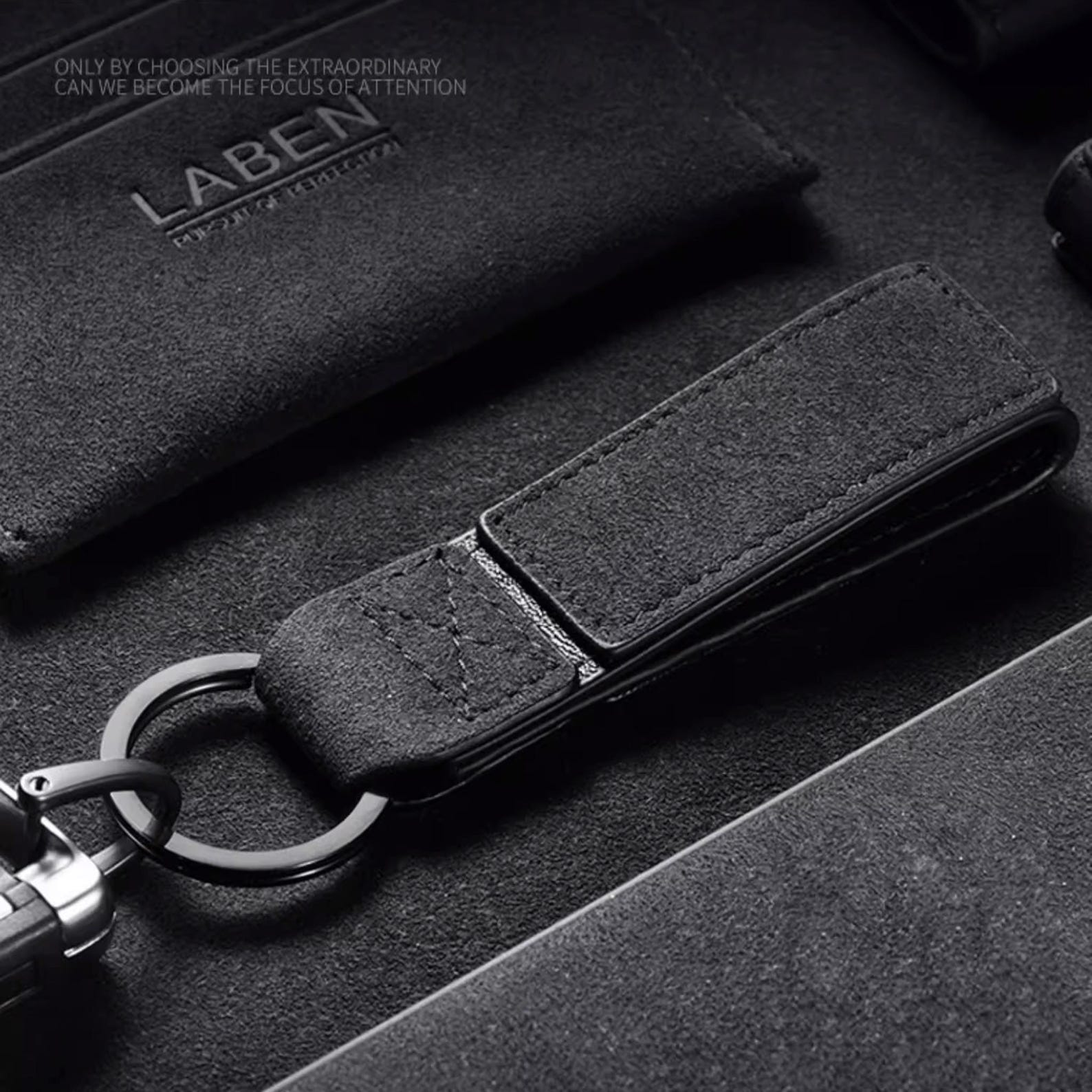 Luxury Alcantara leather car logo keychain on a wooden surface