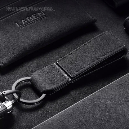 Luxury Alcantara leather car logo keychain on a wooden surface