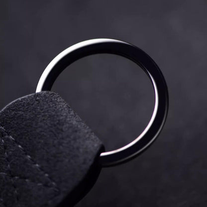 Luxury Alcantara leather car logo keychain on a wooden surface