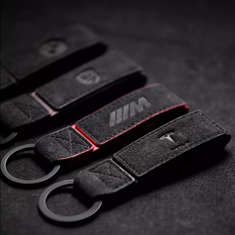 Luxury Alcantara leather car logo keychain on a wooden surface