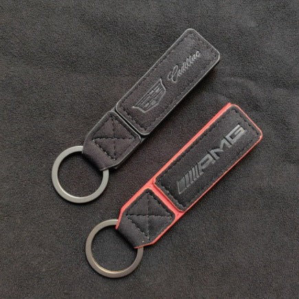 Luxury Alcantara leather car logo keychain on a wooden surface