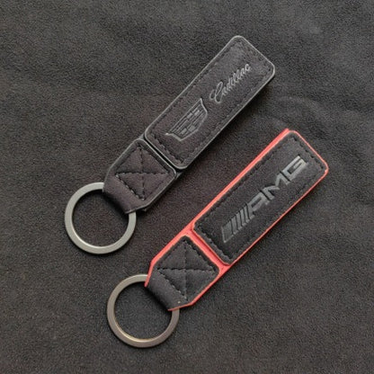 Luxury Alcantara leather car logo keychain on a wooden surface